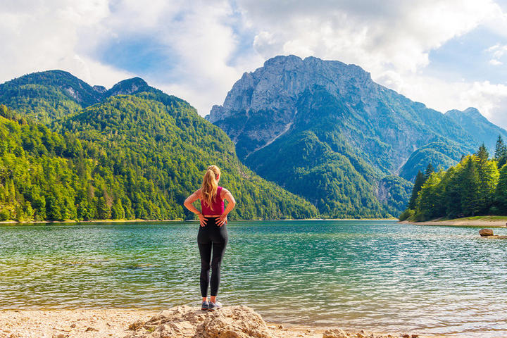 Eine Frau, die Allein vor dem See steht Und die Berge Mit Grüner Natur Betrachtet