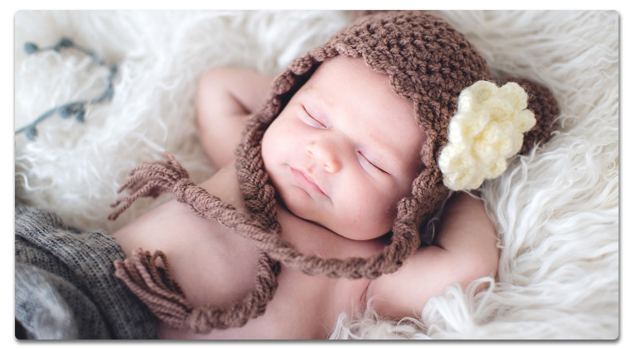 baby mit braun gestrickter mütze am schlafen