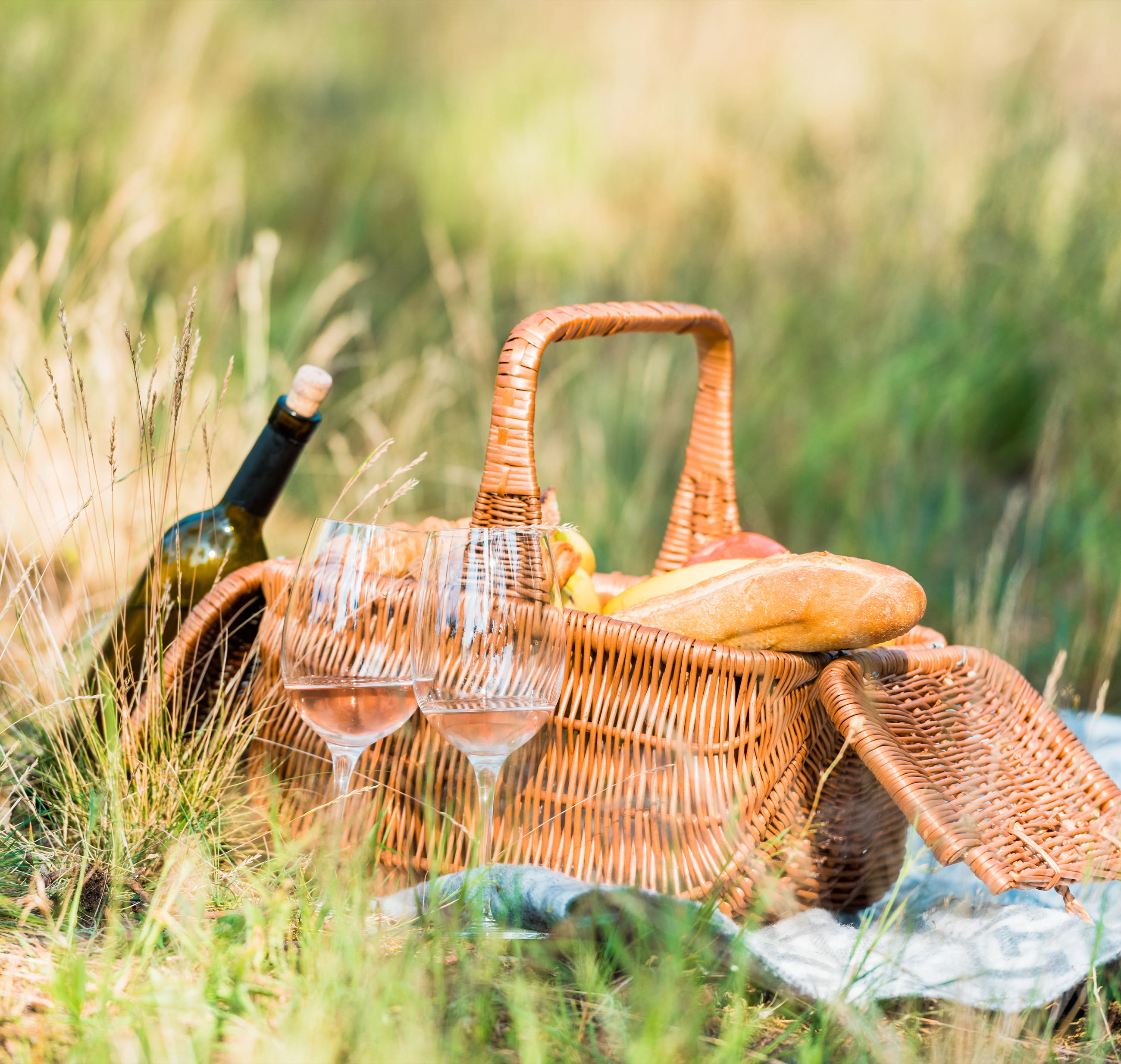 Ein Picknickkorb mit Weingläsern und frischem Brot, ideal für einen entspannten Tag im Freien.