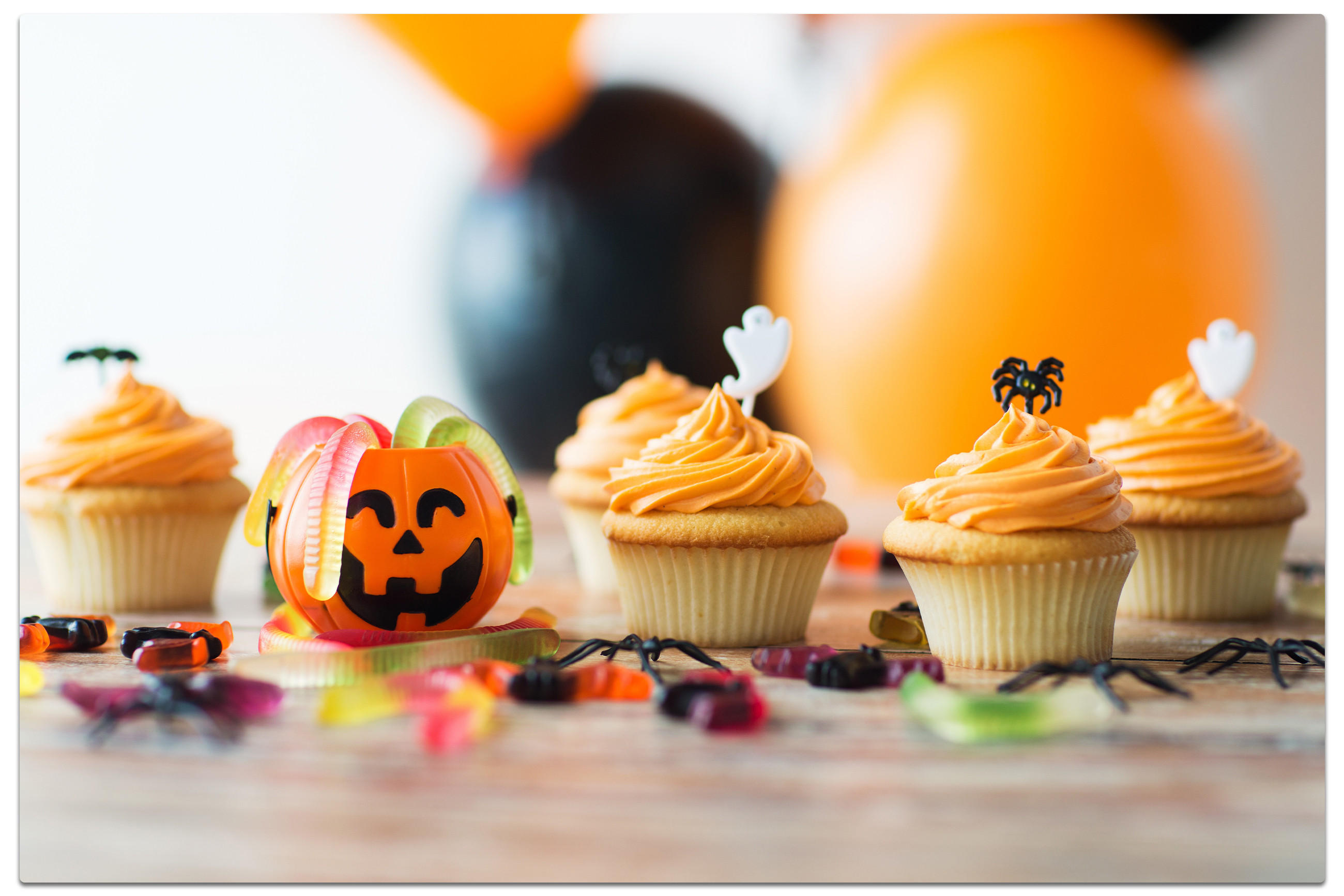 Festliche Halloween-Cupcakes, verziert mit Kürbissen und einer Auswahl an Süßigkeiten.