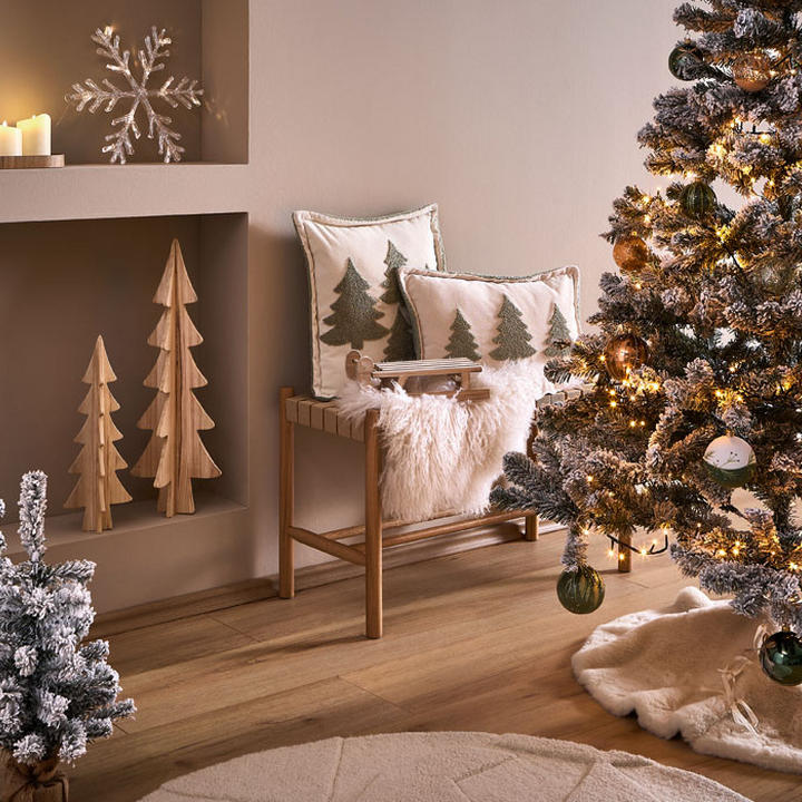 Gemütliches Wohnzimmer mit zwei geschmückten Weihnachtsbäumen, Bank mit Kissen und weihnachtlicher Dekoration.