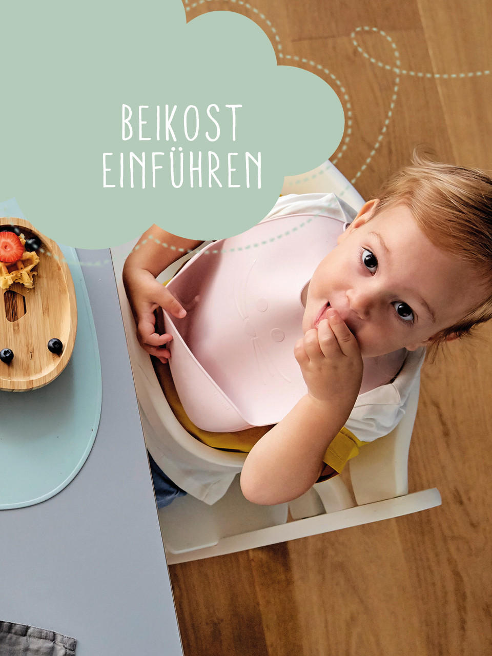 Baby sitzt am Tisch und ist Früchte aus einem tükisenem Teller