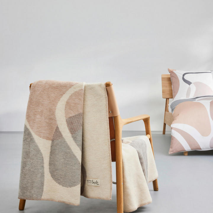 Udoben stol z odejo z vzorcem, ki je nameščena na naslonu.