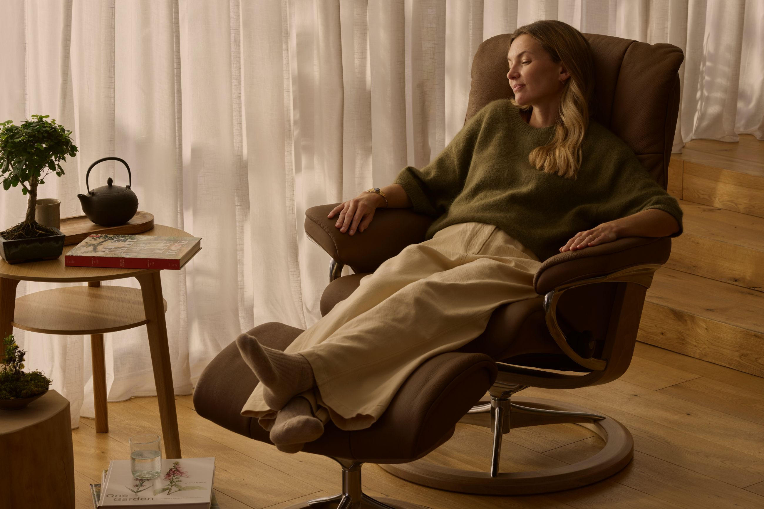 Frau entspannt auf bequemen Relaxsessel von STRESSLESS, mit geschlossenen Augen und hochgelegten Füßen.