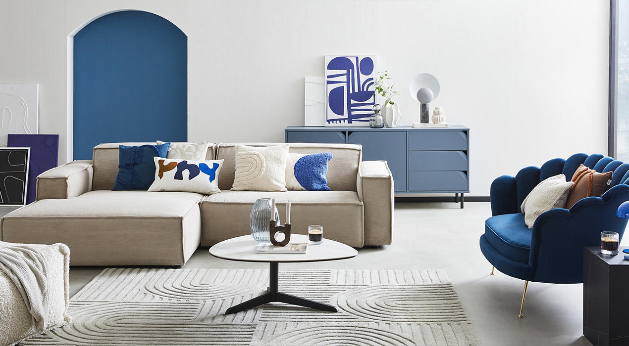 Ecksofa in beige mit Kissen in blau