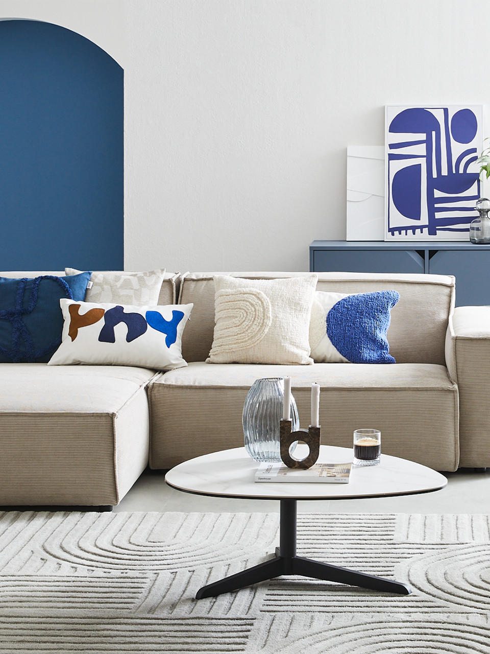 Ecksofa in beige mit Kissen in blau
