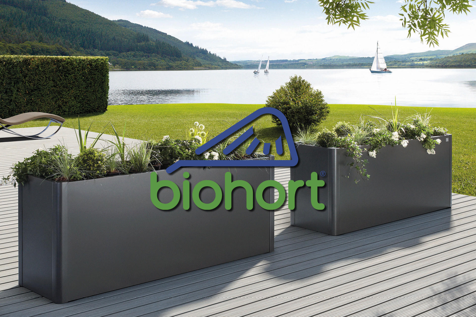 Hochbeete aus Aluminium der Marke Biohort auf einer sonnigen Terrasse mit einer grünen Wiese im Hintergrund
