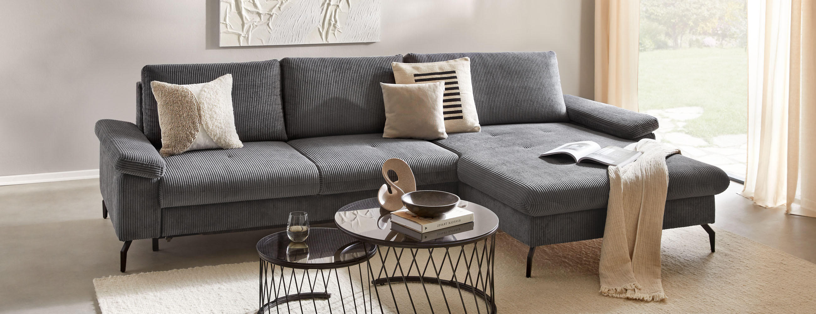 Modernes Wohnzimmer mit grauem Sofa, Couchtischen und Wandkunst.