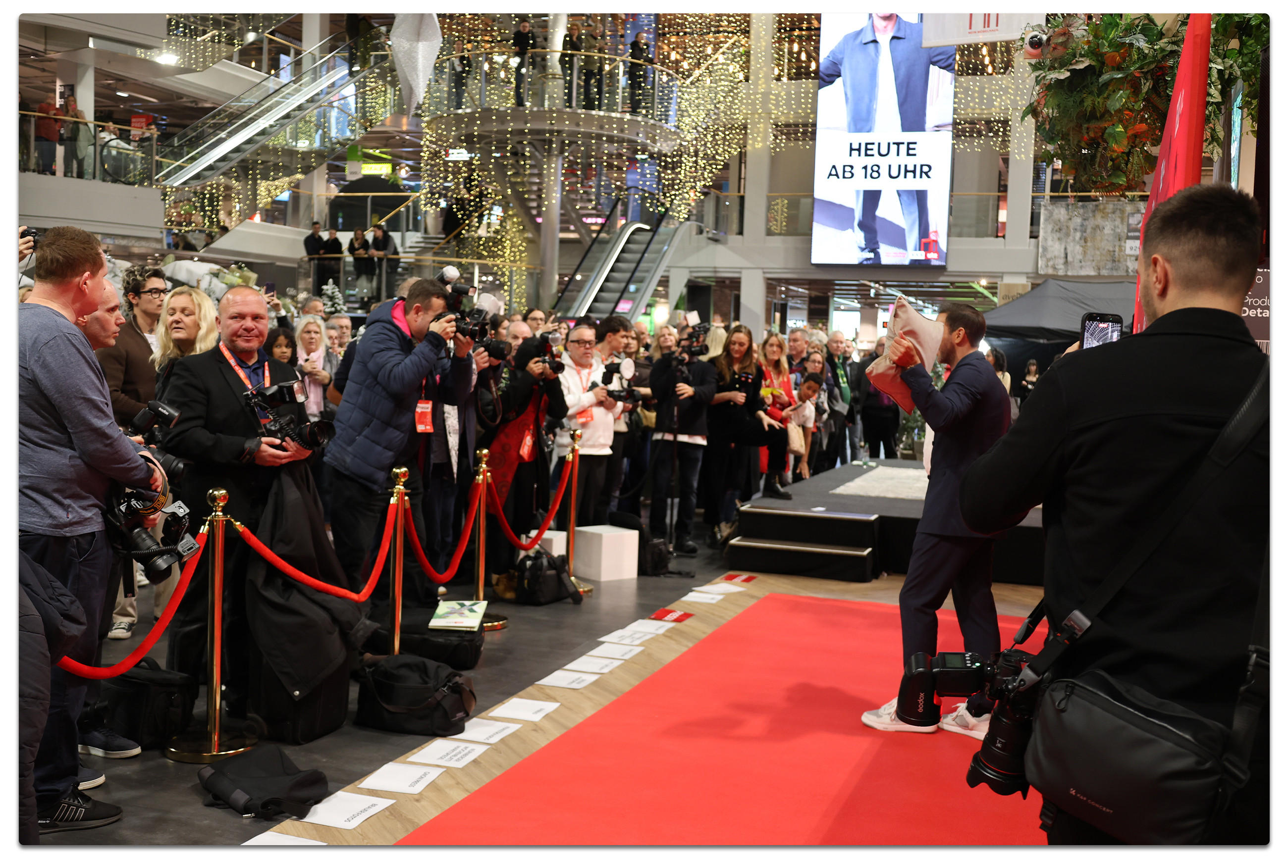 Marcel Remus auf dem roten Teppich im XXXLutz Einrichtungshaus, umgeben von Fotografen und Gästen bei der Präsentation seiner Bettwäsche-Kollektion.