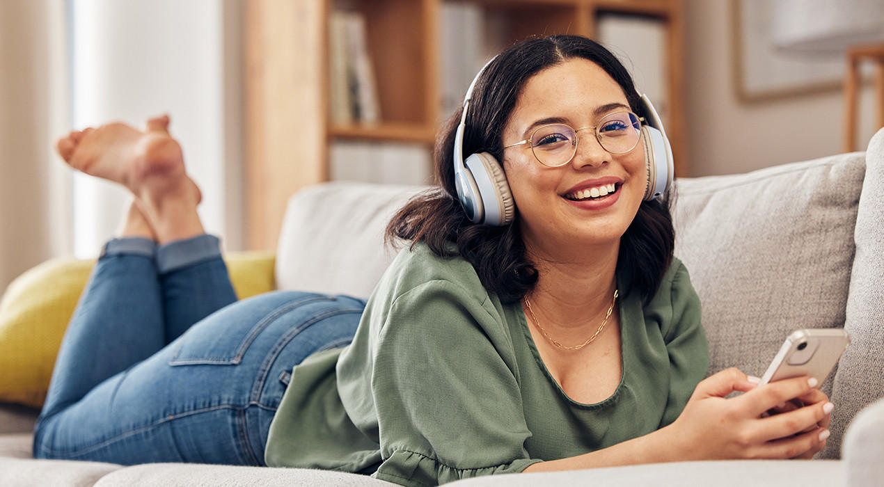 Mädchen liegt auf Bett und hört Podcast