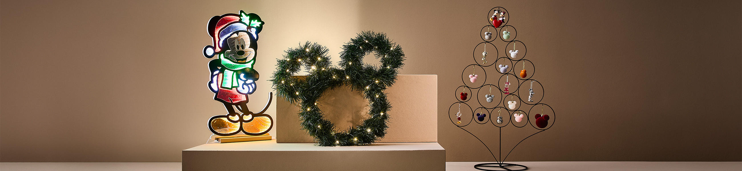 Mickeymouse mit einem Weihnachtsbaum in bunt auf einem Podest