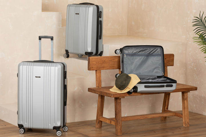 Drei Reisekoffer, Auf einer Holzbank liegen ein Reisekoffer und ein Hut