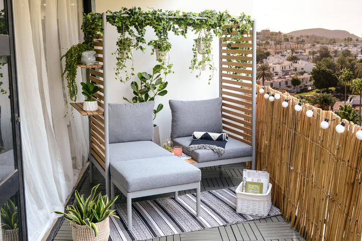 Balkon mit grauer Sitzgelegenheit und grünen Hängepflanzen