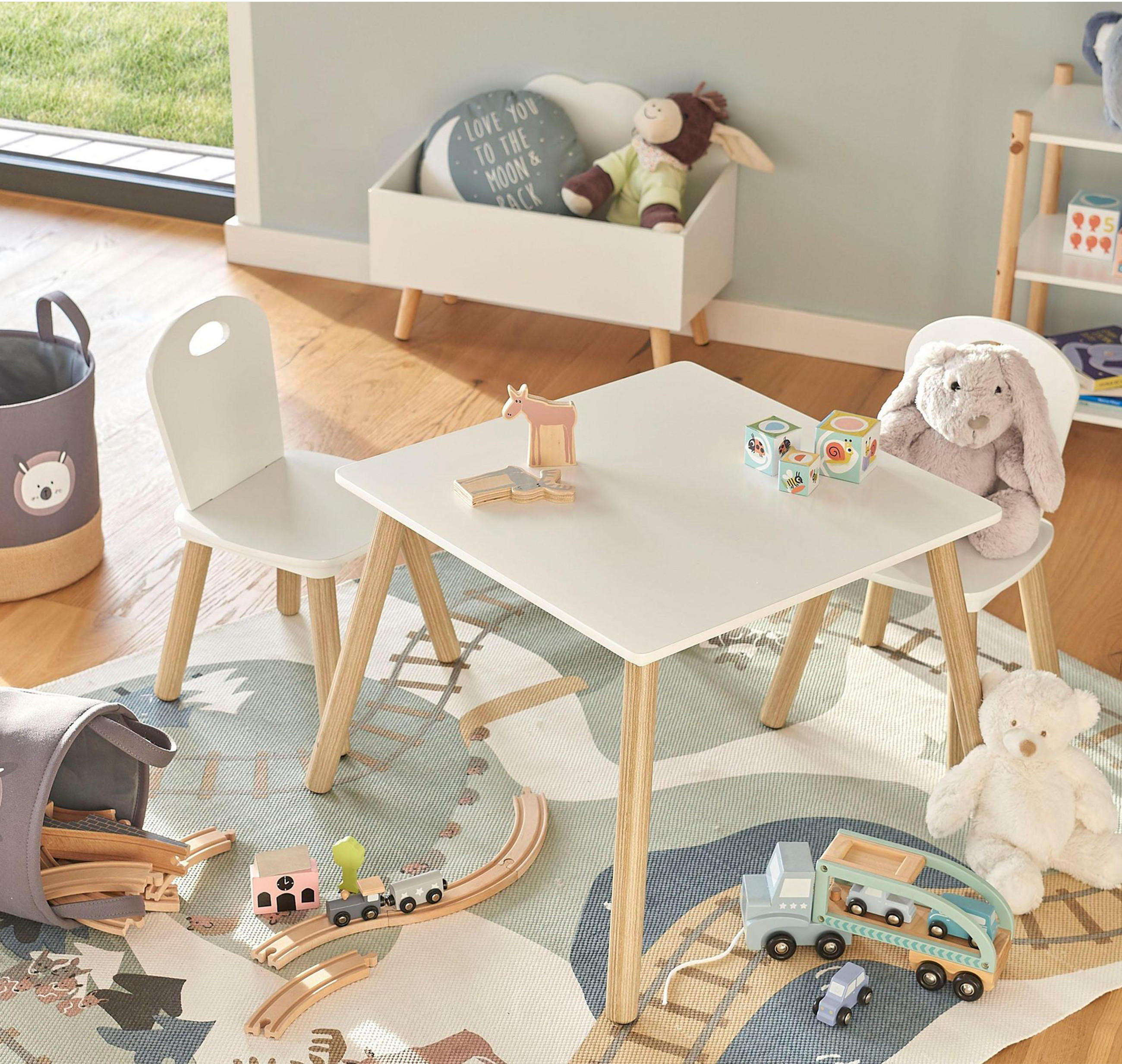 Spielecke für Kinder im Wohnzimmer mit Tischgruppe, Teppich, Aufbewahrungsmöglichkeiten und eine Menge Spielzeug.