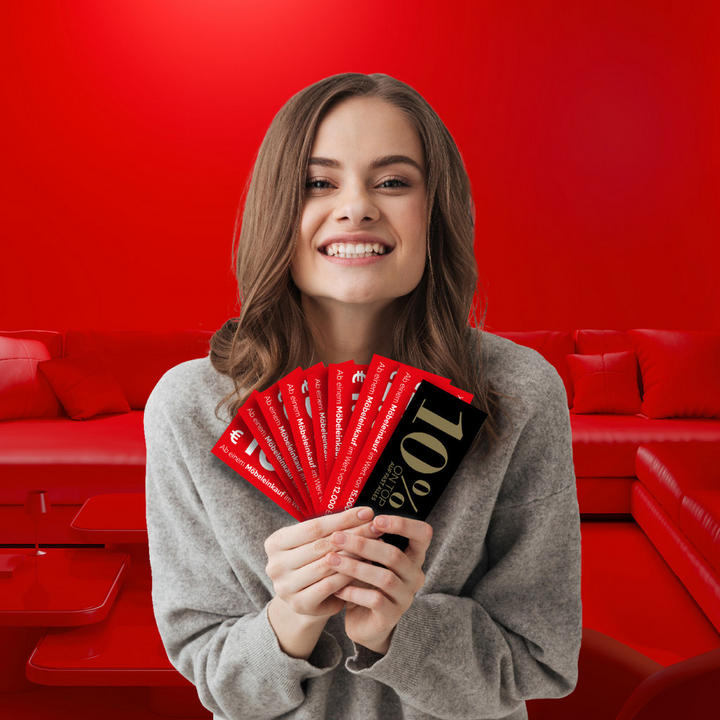 Eine Frau vor einem roten Hintergrund mit XXXLutz Gutscheinen in der Hand