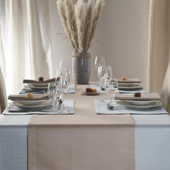 Miza s belim prtom in urejenimi krožniki ter priborom.