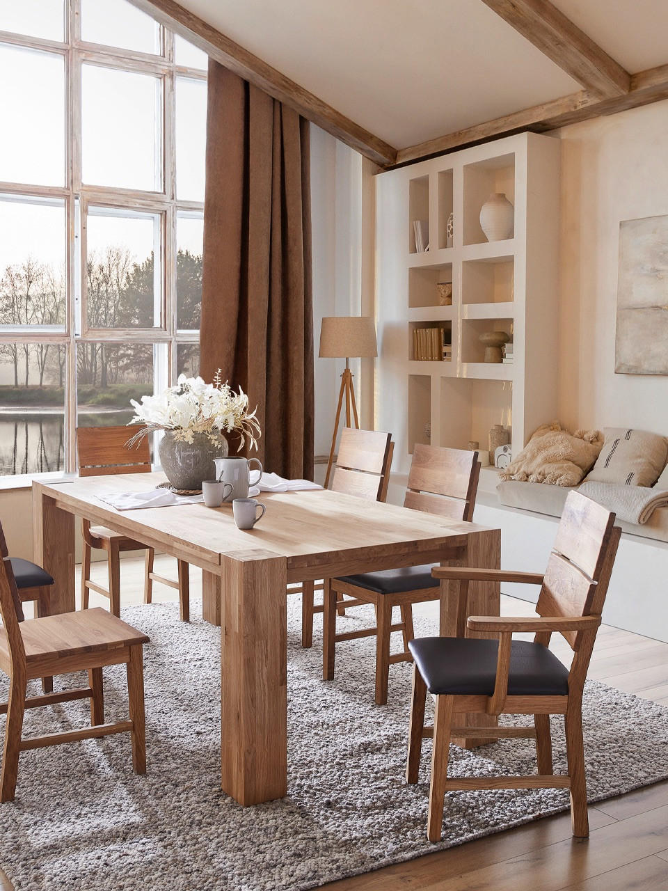 Esszimmer mit braunem Massivholztisch und einem großen Fenster im HIntergrund