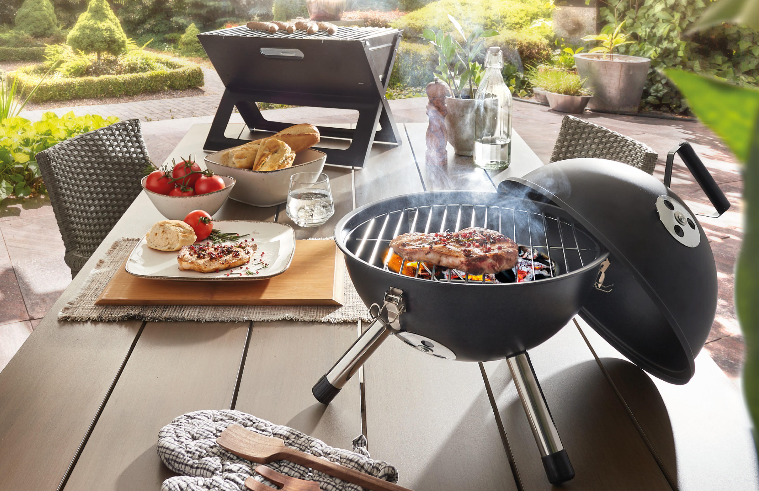 Tischgrill mit gedecktem Holzesstisch im Garten