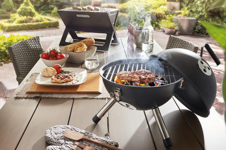 Tischgrill mit gedecktem Holzesstisch im Garten