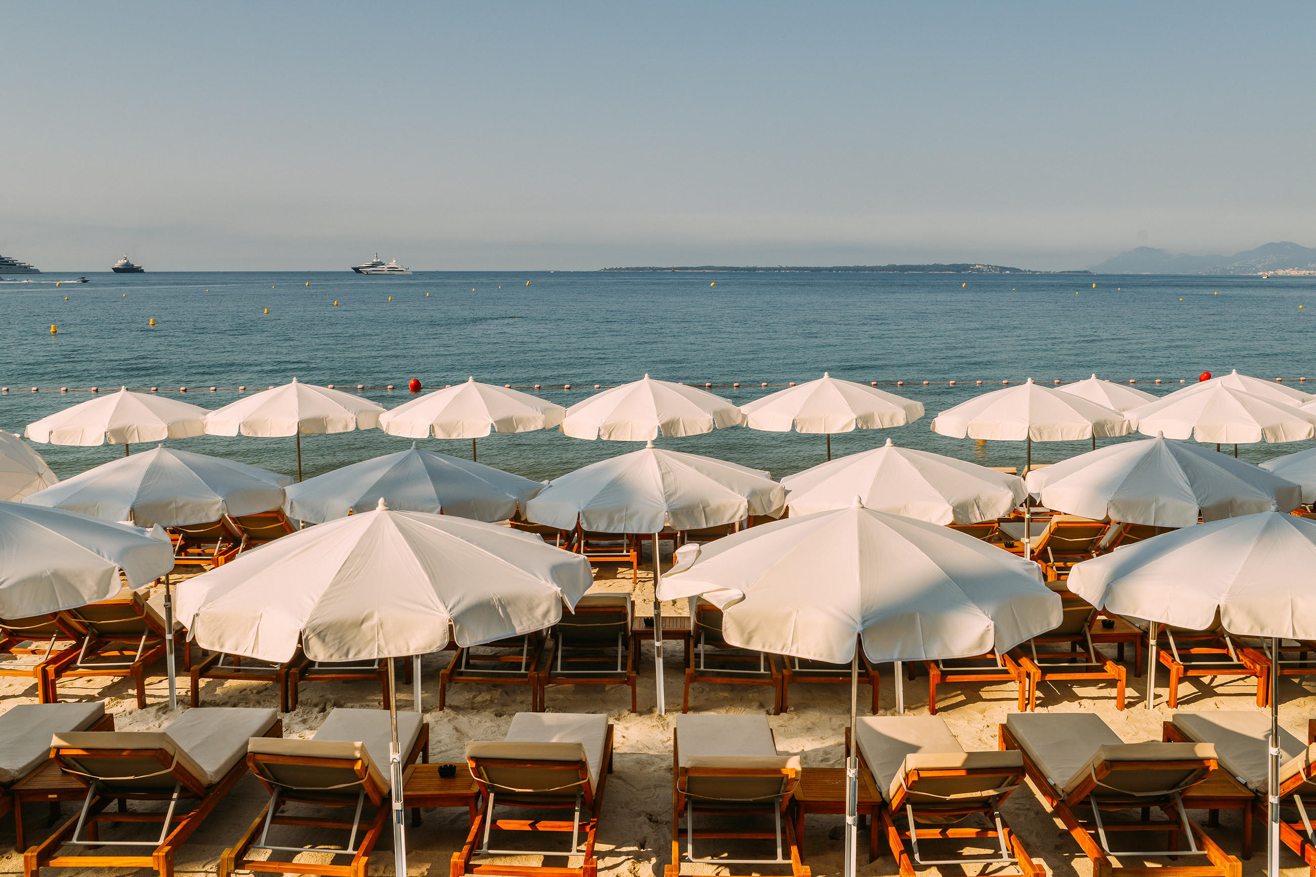 Strand mit weißen Sonnenschirmen und Liegen an der Französischen Riviera.