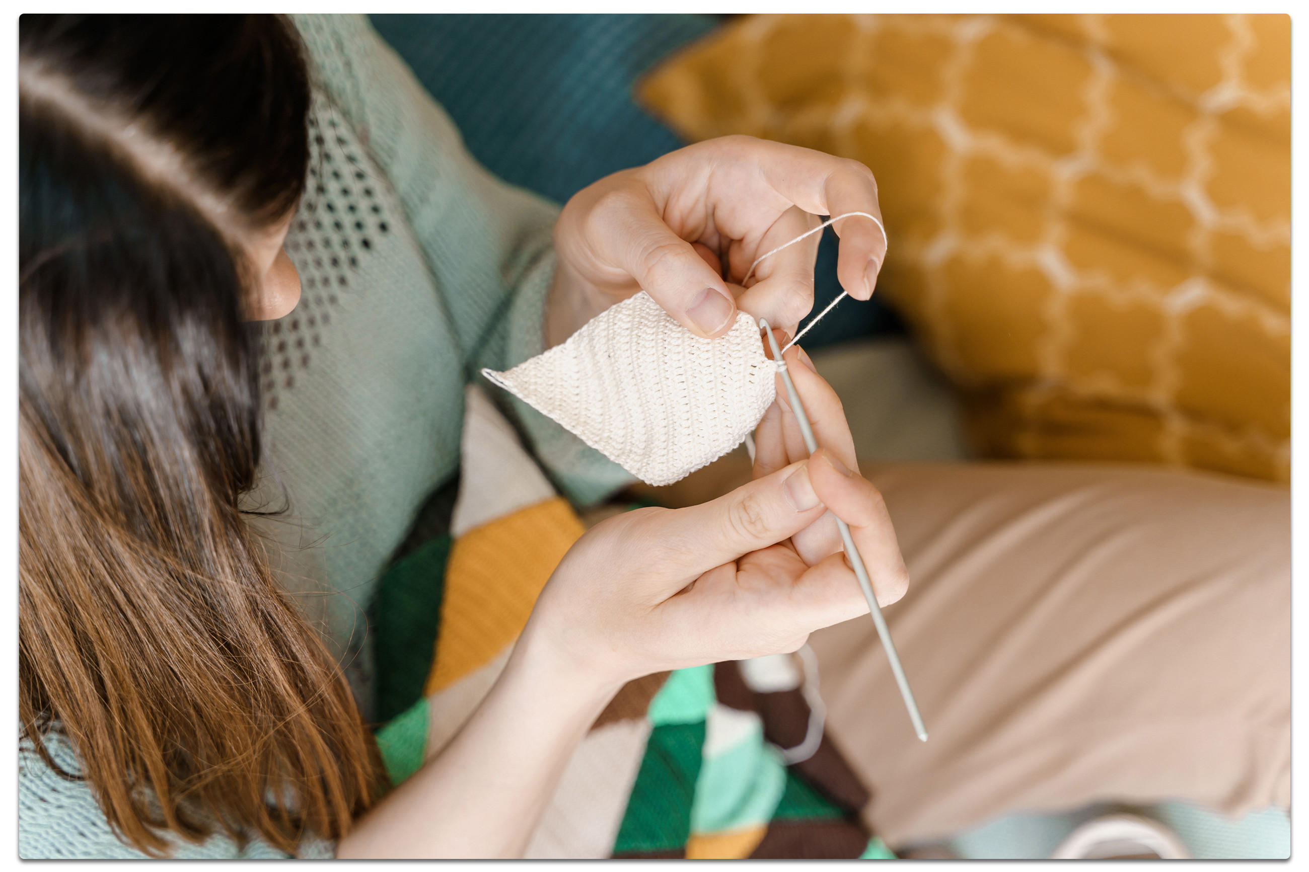 Eine Frau strickt mit einer Häkelnadel in der Hand, um ihr DIY-Projekt zu vervollständigen.