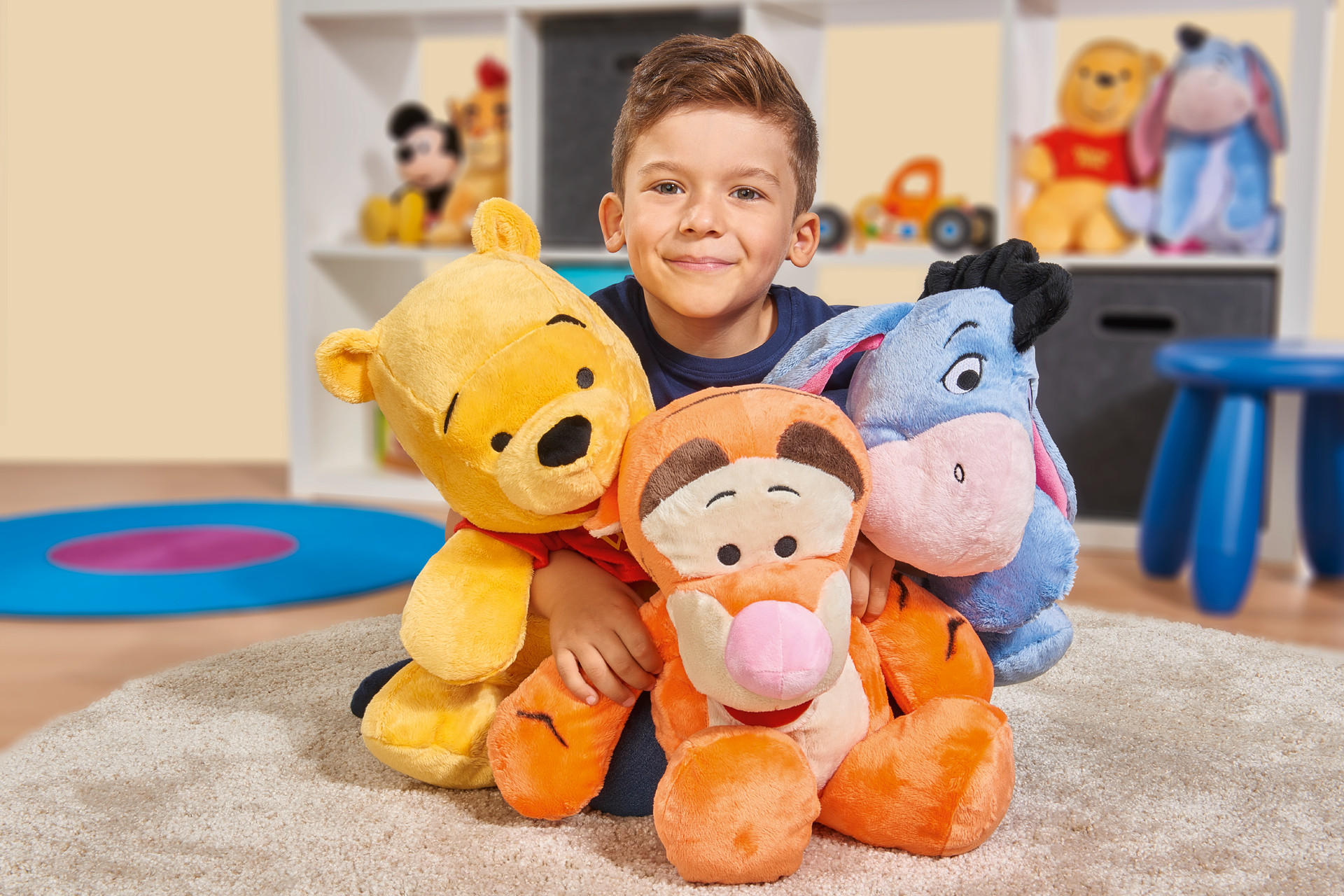 Glückliches Kind mit Stofftieren Winnie Puh, I-Ah und Tigger