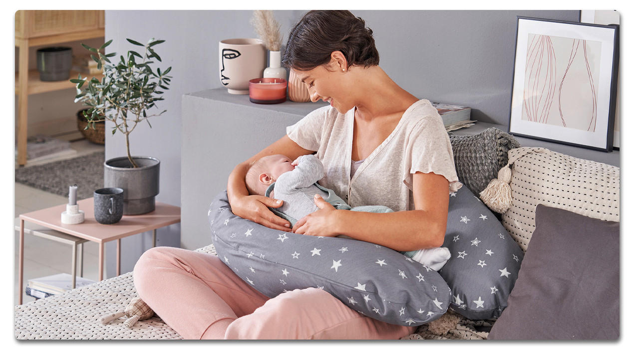 frau stillt baby mit grauem stillkissen