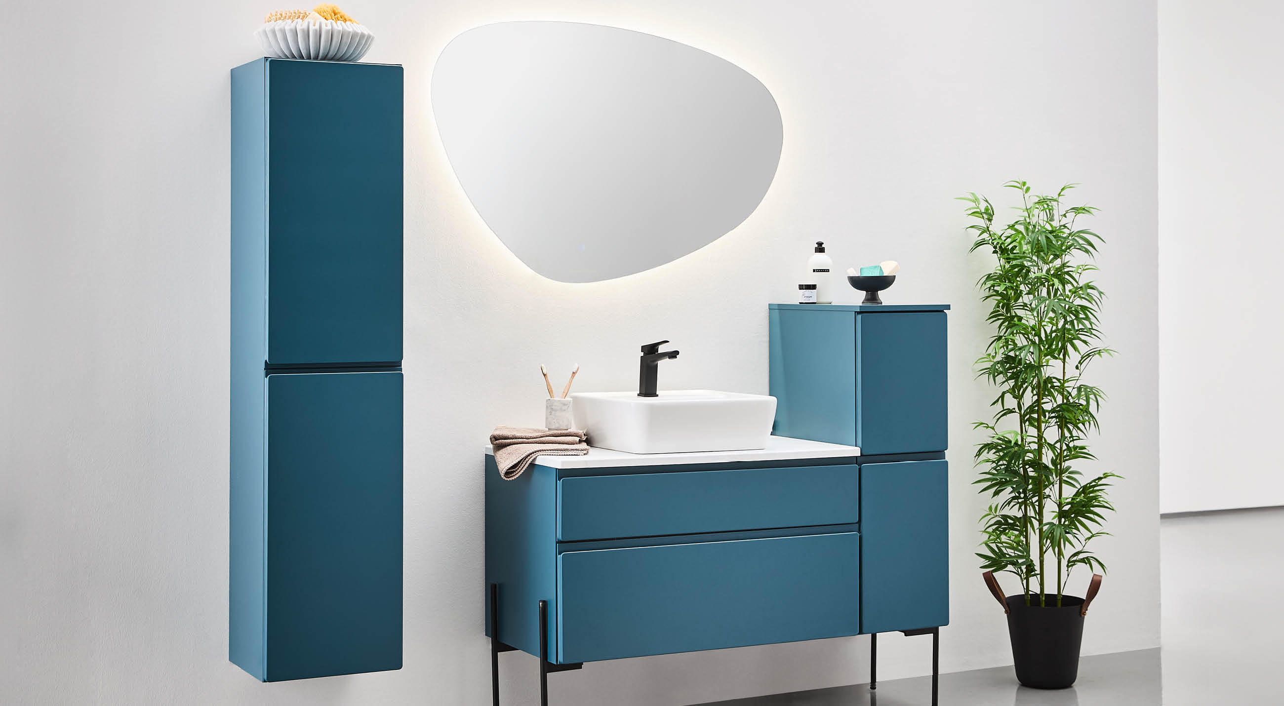 Modernes Badezimmer mit blauen Möbeln, einschließlich eines blauen Schranks und eines Waschbeckens, in freundlicher Atmosphäre.