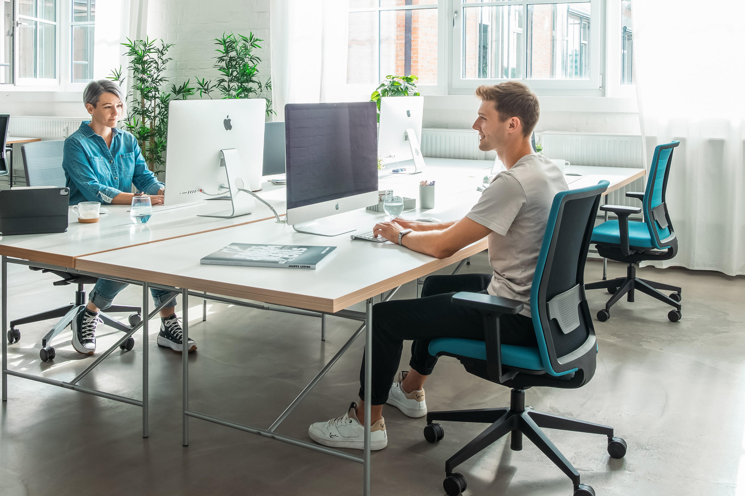 Zwei Personen in einem Büro mit Schreibtischen und Drehstühlen der Marke TOPSTAR.