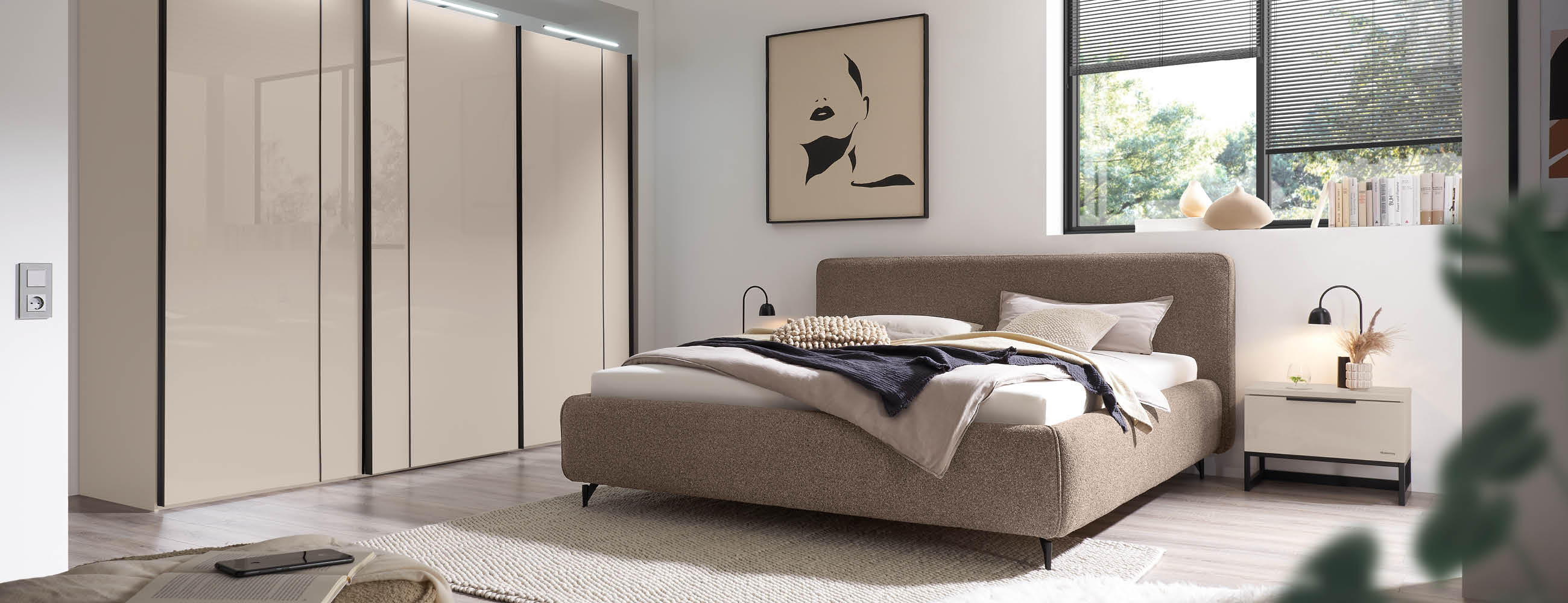 Ein gemütliches Schlafzimmer mit einem Bett aus Stoff, einem Kleiderschrank mit integrierten Licht und einem Fenster, das den Blick nach draußen ermöglicht.