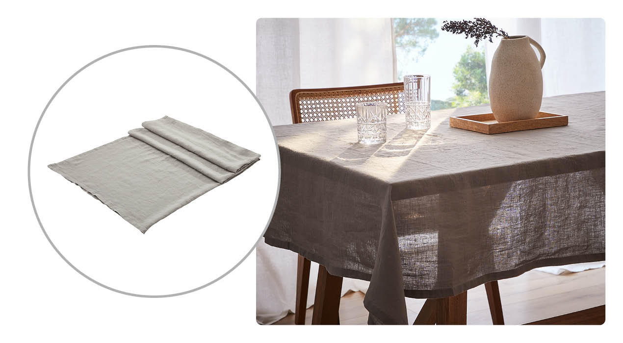 Schlichte, hellgraue Tischdecke aus leicht strukturiertem Stoff sowie Wohnszene mit derselben Tischdecke auf einem Esstisch, dekoriert mit zwei Gläsern und einer cremefarbenen Vase auf einem Holztablett in sanftem Sonnenlicht.