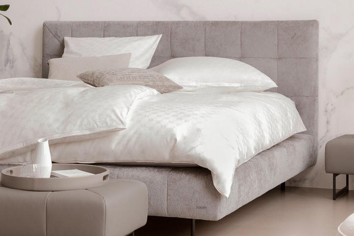 graues Boxspringbett mit hellen Kissen