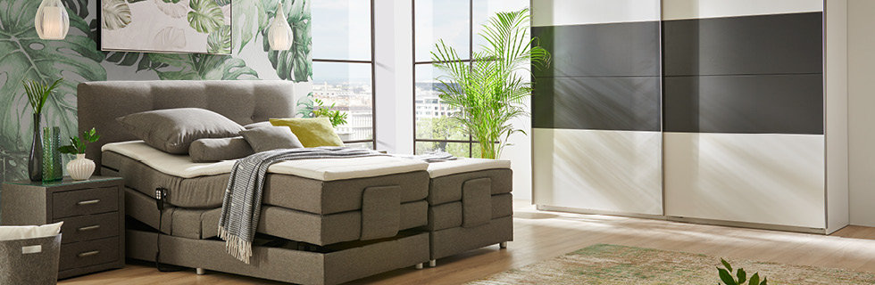 Graues Boxspringbett mit Pflanzenmotiv