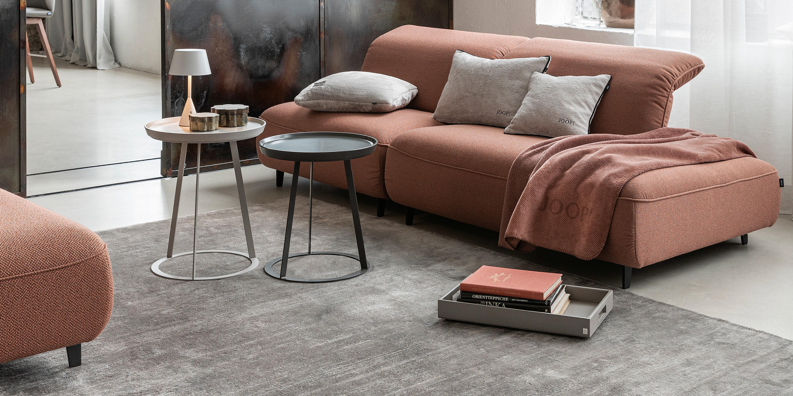 Großer JOOP! Teppich in Greige in einem stilvoll eingerichtetem Wohnzimmer mit Sofas und Beistelltischen.