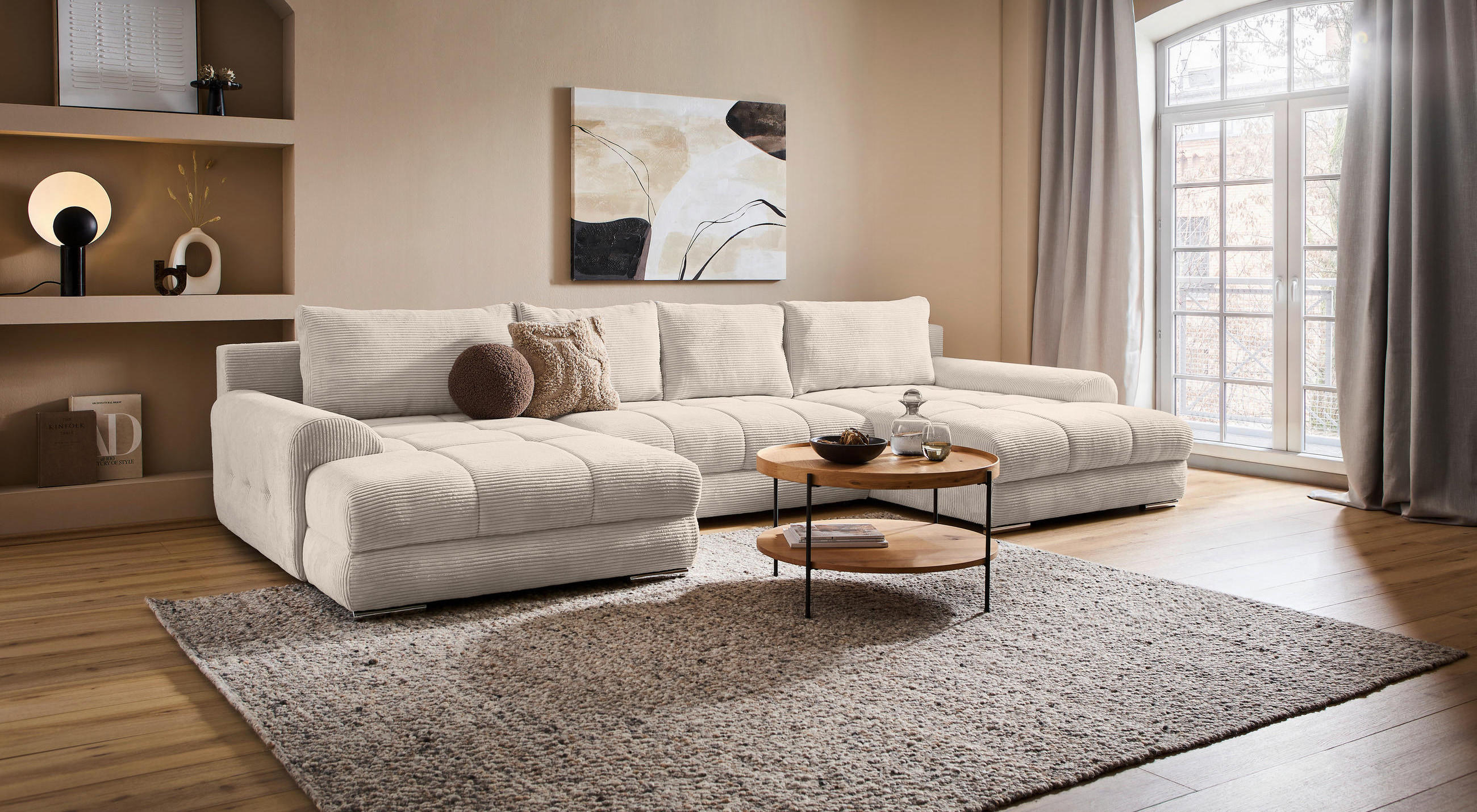 Wohnzimmer mit brauner Wand, Cordsofa in creme und schwarzen Akkzenten. 
