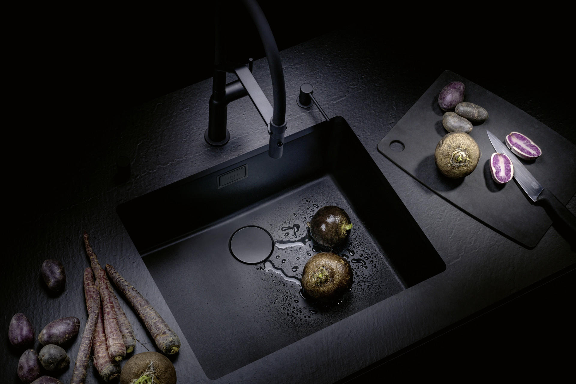 Schwarze und elegante Spüle von Suter mit Gemüse und Wasser