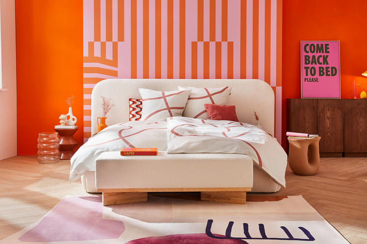 Modernes Schlafzimmer mit warmen orangefarbenen Wänden und einem weißen Bett in der Mitte.