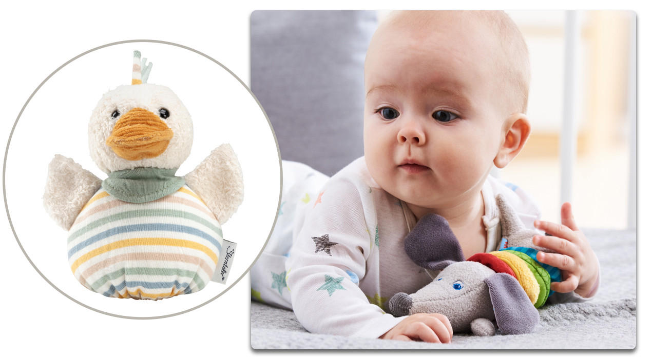 baby auf dem Boden mit rassel in der Hand