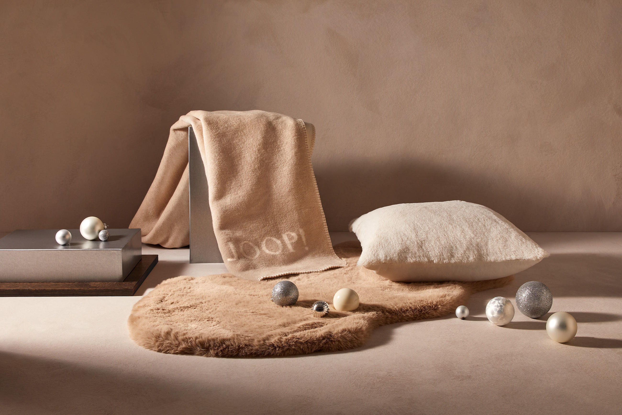 Kuscheldecken und Kissen in weihnachtlicher Atmosphäre mit Christbaumkugeln