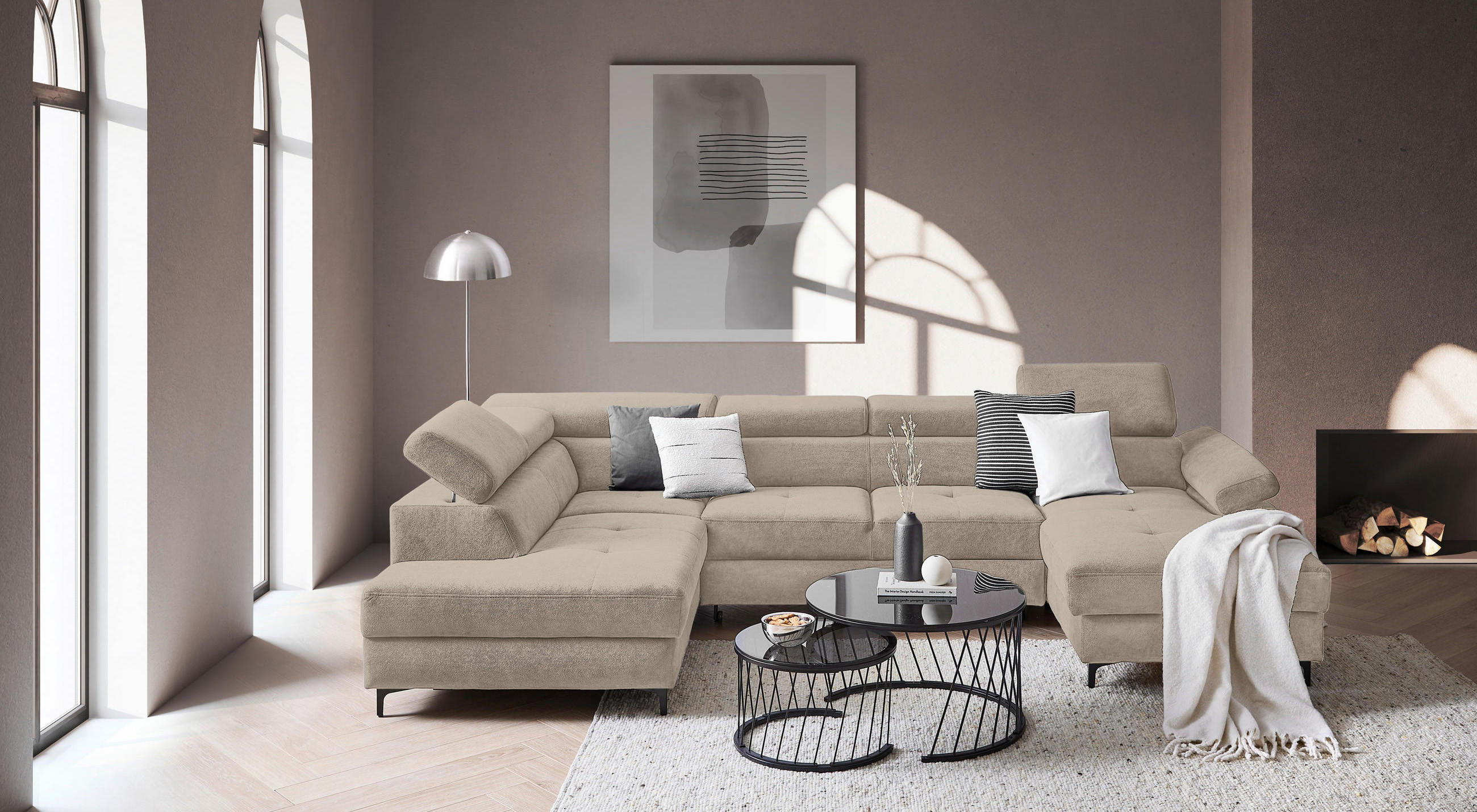 Beige Wohnlandschaft mit schwarzem COuchtisch vor altrosaner Wand mit Poster.