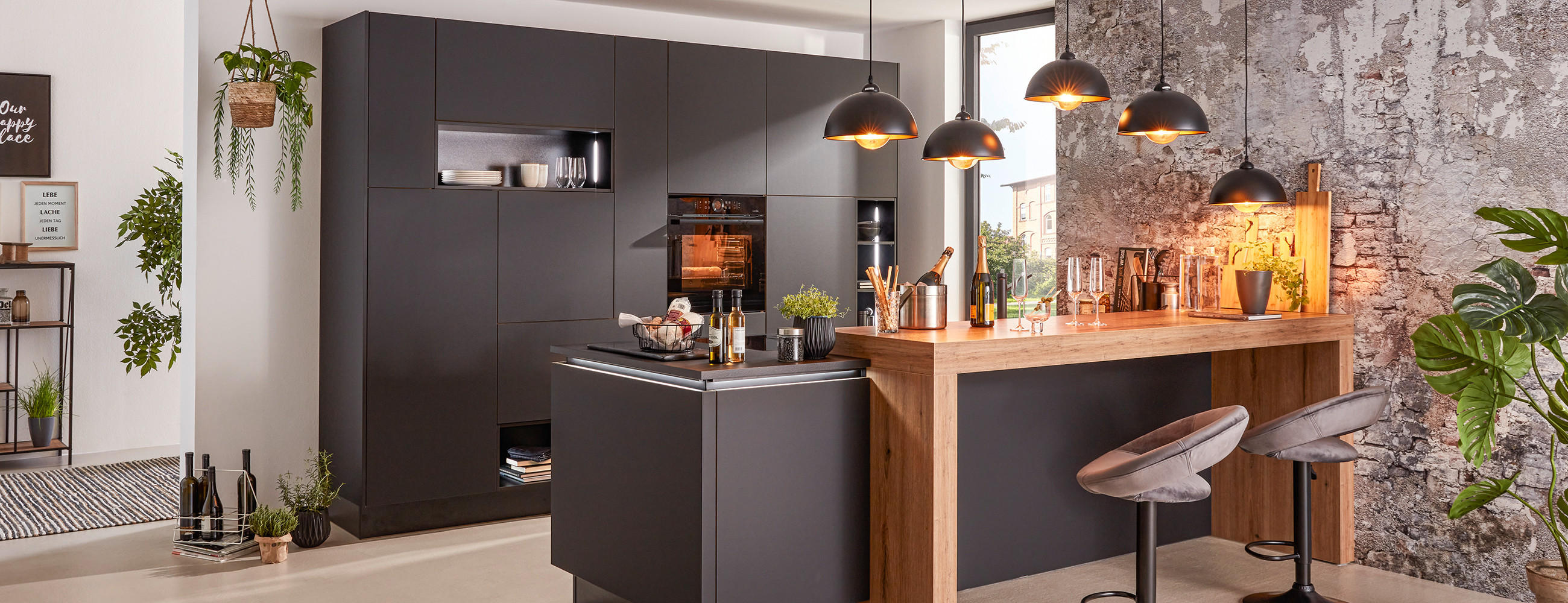 Dunkle Küche in G-Form mit Holzthek, Barhockern, sowie modernen Hängeleuchten.