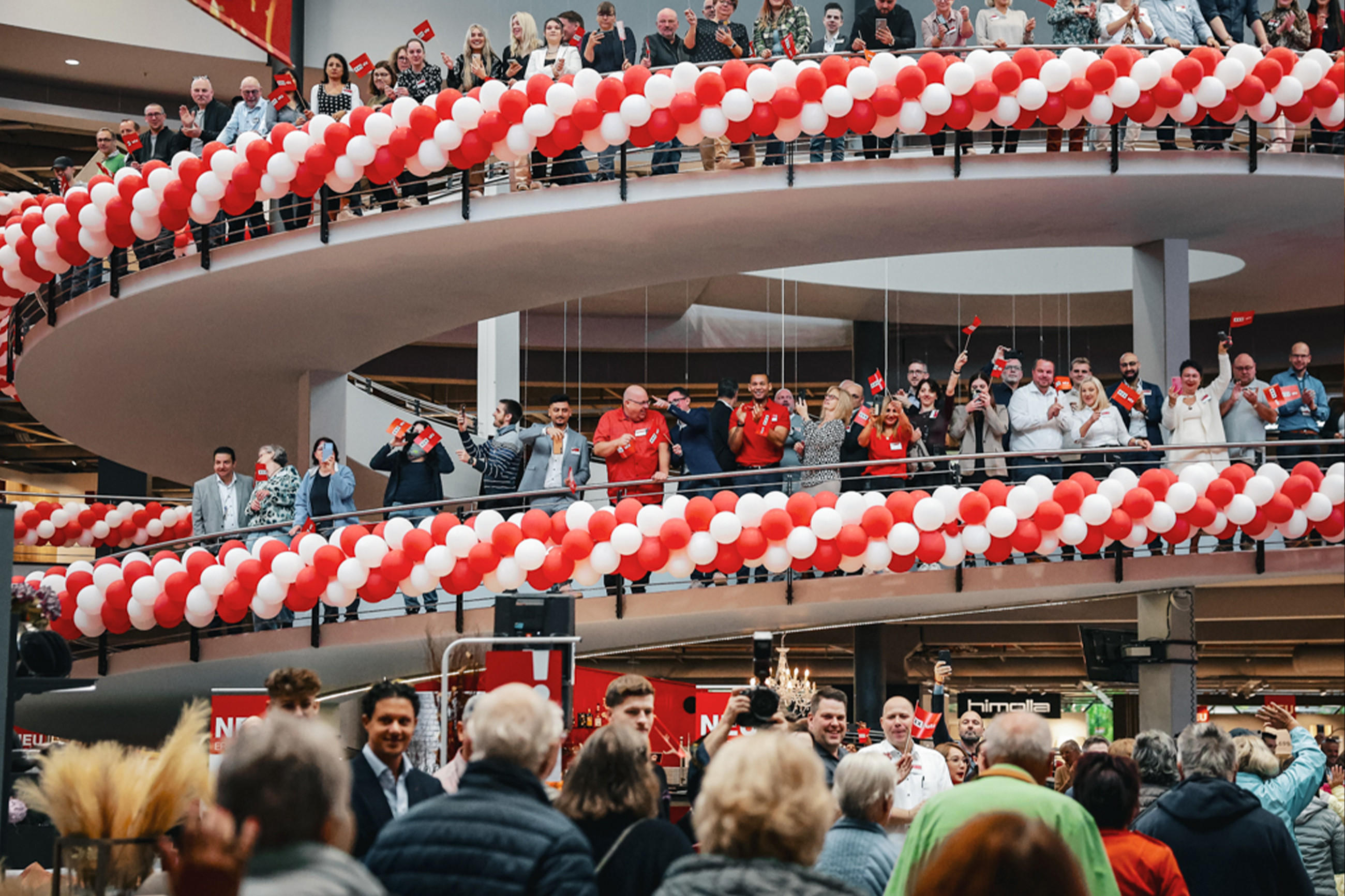 Eine lebhafte Ansammlung von Menschen bei  der Eröffnung von XXXLutz Hesse, die mit bunten Ballons eine fröhliche Stimmung erzeugt. 