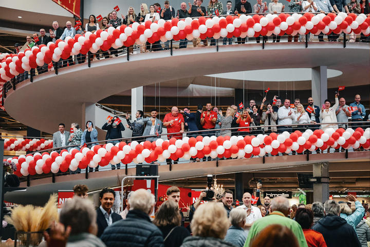 Eine lebhafte Ansammlung von Menschen bei der Eröffnung von XXXLutz Hesse, die mit bunten Ballons eine fröhliche Stimmung erzeugt.