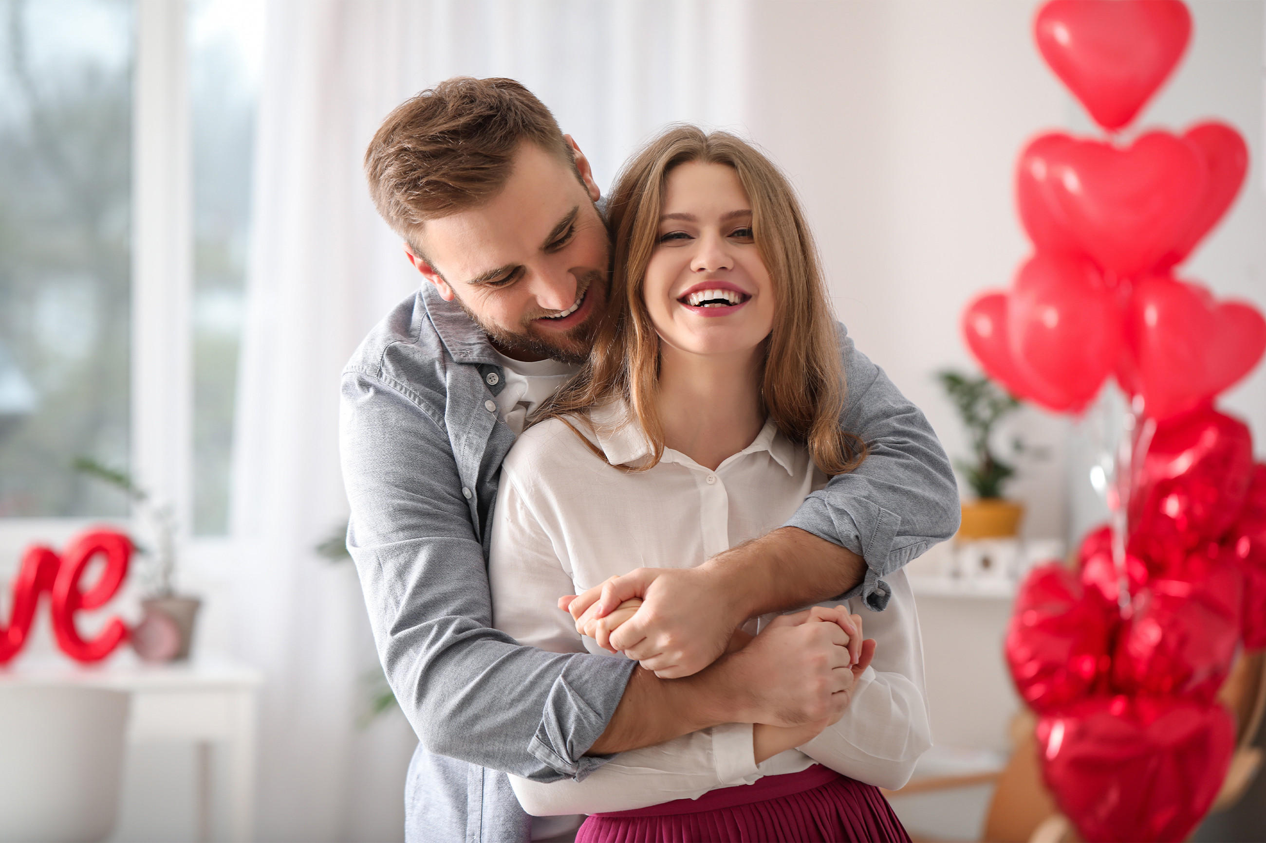 Ein Paar umarmt sich liebevoll vor einem Herz, das den Valentinstag symbolisiert.
