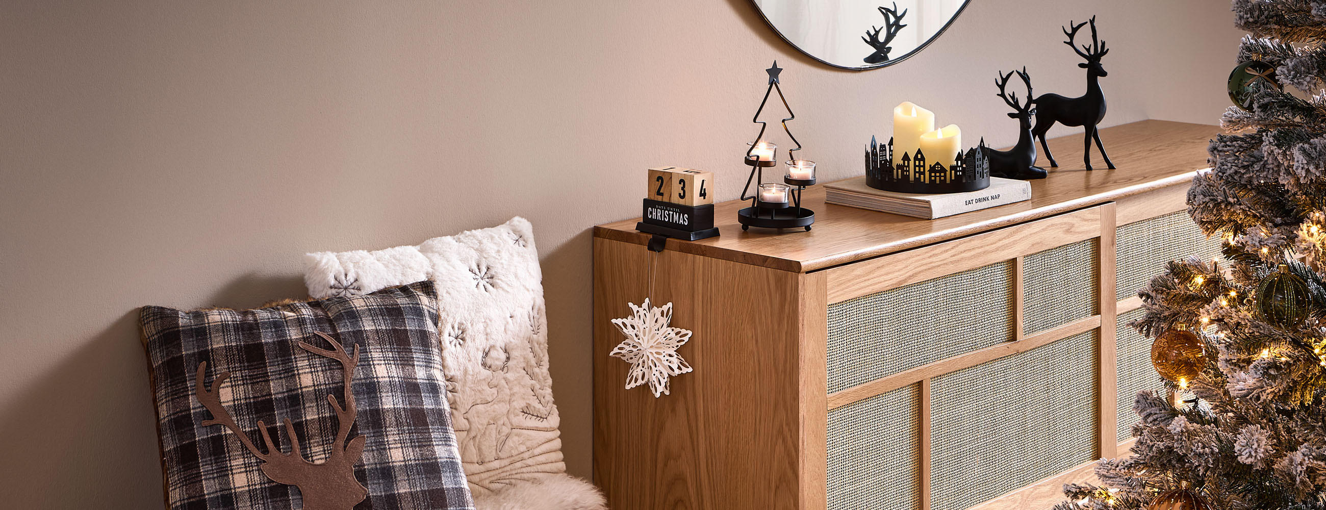 Weihnachtlich dekorierte Kommode mit Spiegel, Kissen und Tannenbaum.