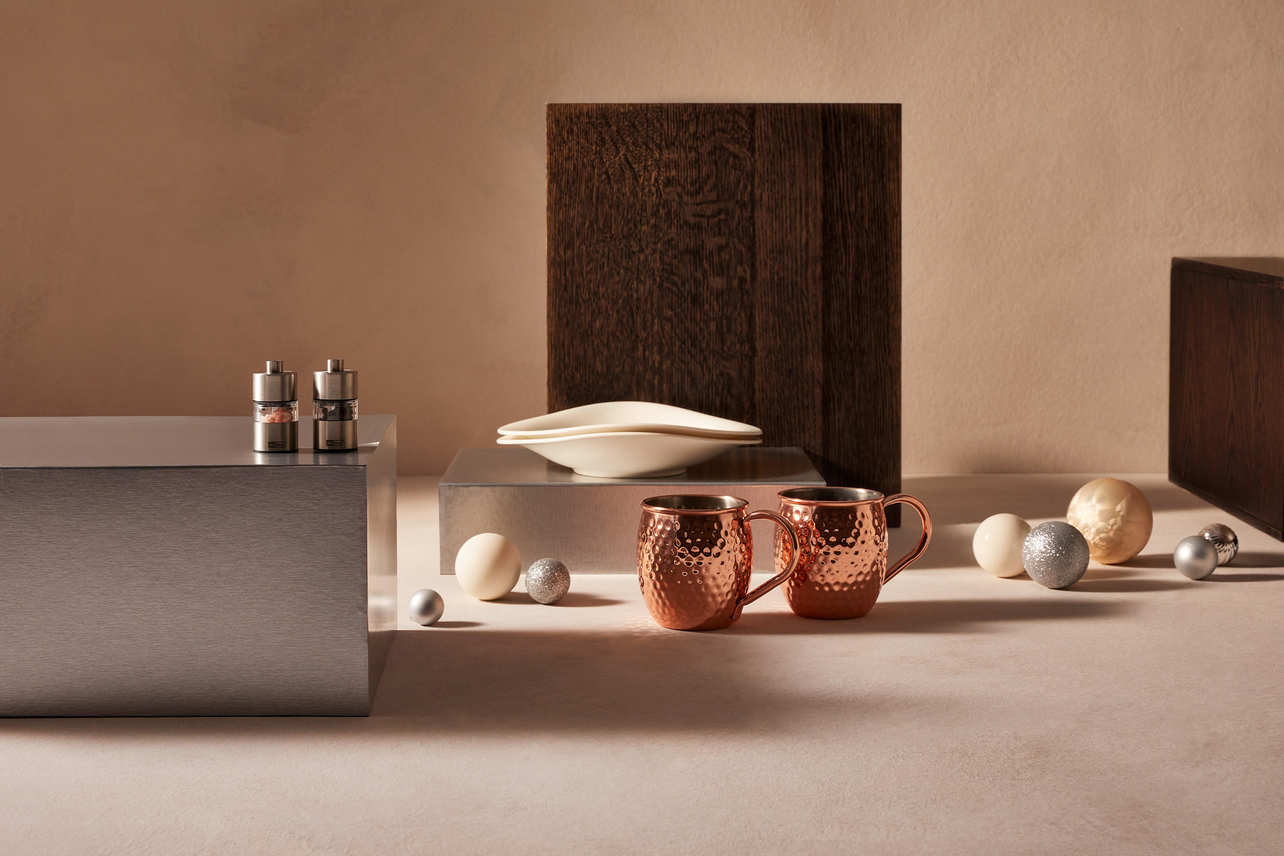 Salz- und Pfefferstreuer und zwei goldene Tassen in weihnachtlicher Atmosphäre mit Christbaumkugeln