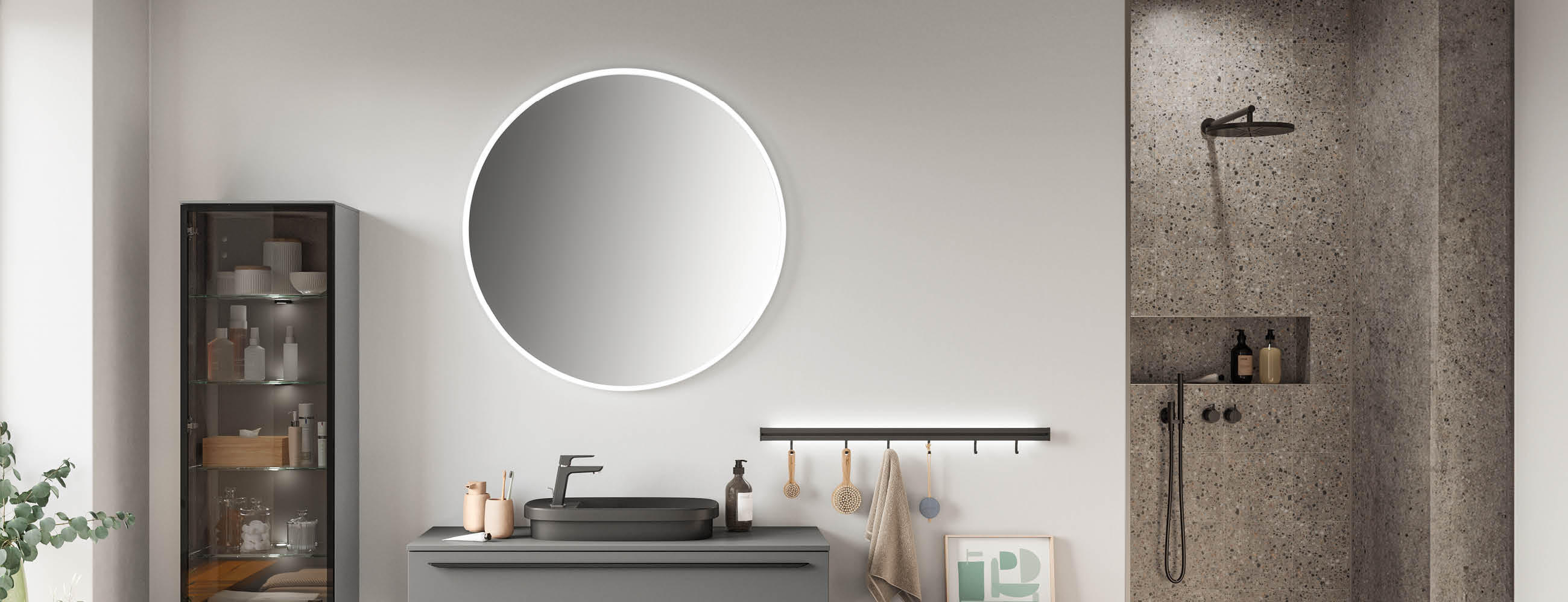 Modernes Badezimmer mit rundem beleuchtetem Spiegel, grauem Waschtisch, schwarzem Armatur, Glasvitrine links und begehbarer Dusche mit Regenduschkopf rechts