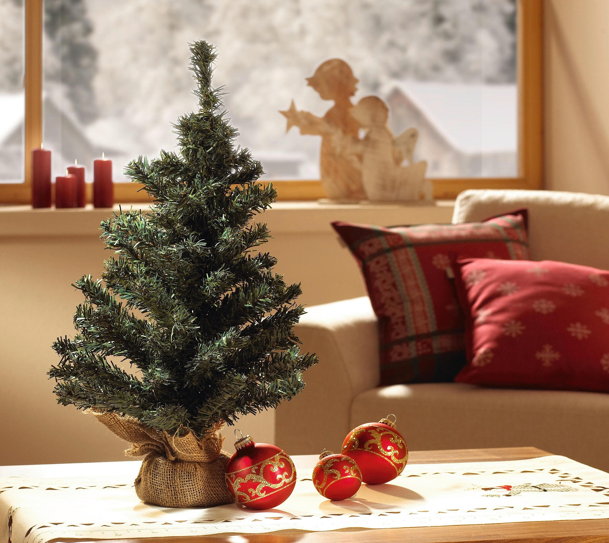 Majhna božična jelka okrašena z lučkami in okraski.