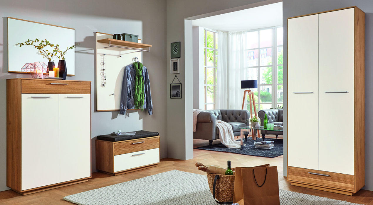 Heller Wohnbereich aus weißen und holzfarbenen Möbeln, Spiegel, Sitzbank, Deko und angrenzendem Wohnzimmer