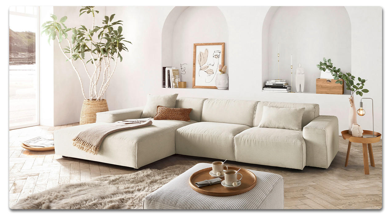 beige couch mit decke und hocker daneben